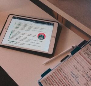 An iPad displaying hand written notes next to a notepad. Apprenticeship